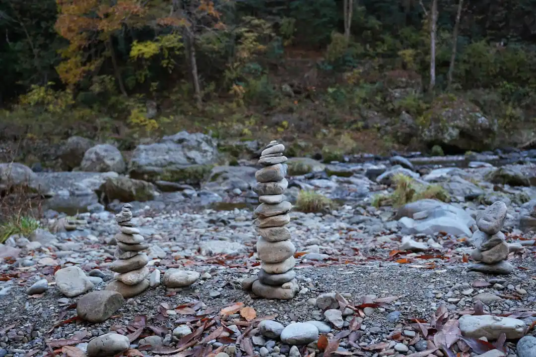 강가의 바위 위에 여러 개의 조약돌이 균형을 맞추며 쌓여 있다.