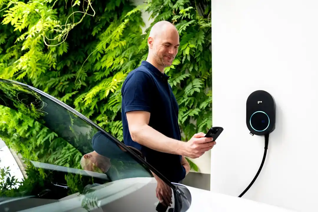 一名男子在為他的電動車充電時,正在查看他的手機。