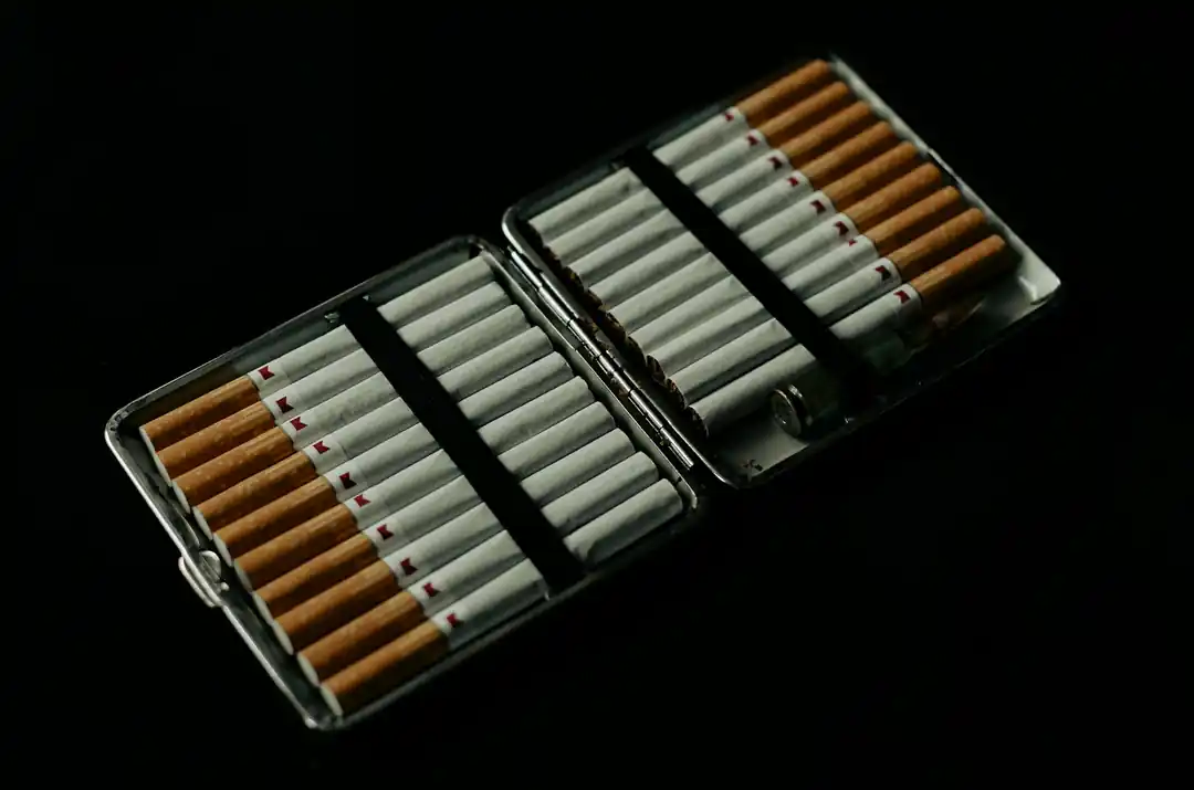 A close-up of a cigarette with ash, highlighting textures and patterns of burning tobacco.