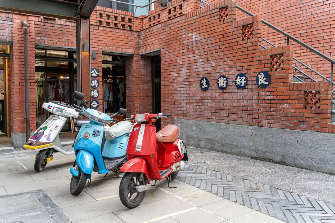 三台色彩鮮豔的共享機車停在宜蘭傳統藝術中心的紅磚建築前。