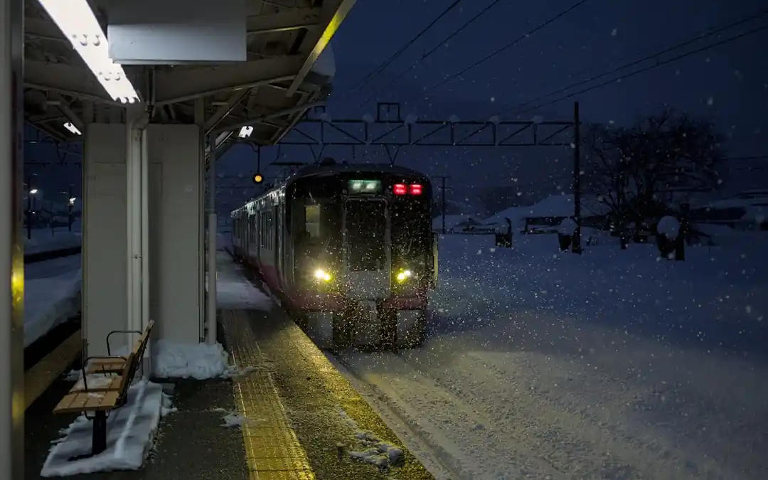 雪が降る夜の駅に到着する列車