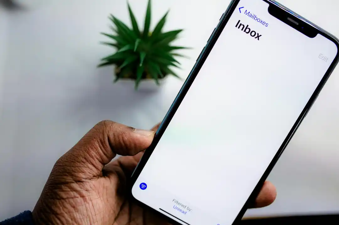 A close-up of a person holding a smartphone, with a clean and organized email inbox displayed on the screen.
