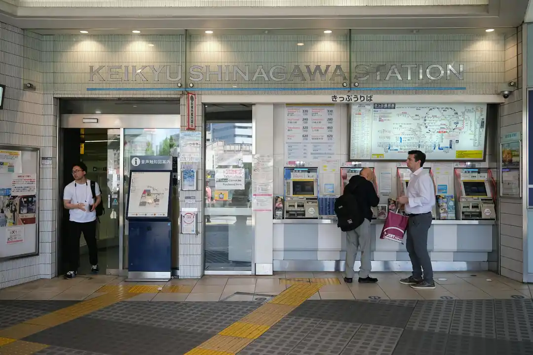 東京の品川駅で券売機の前に立つ人々