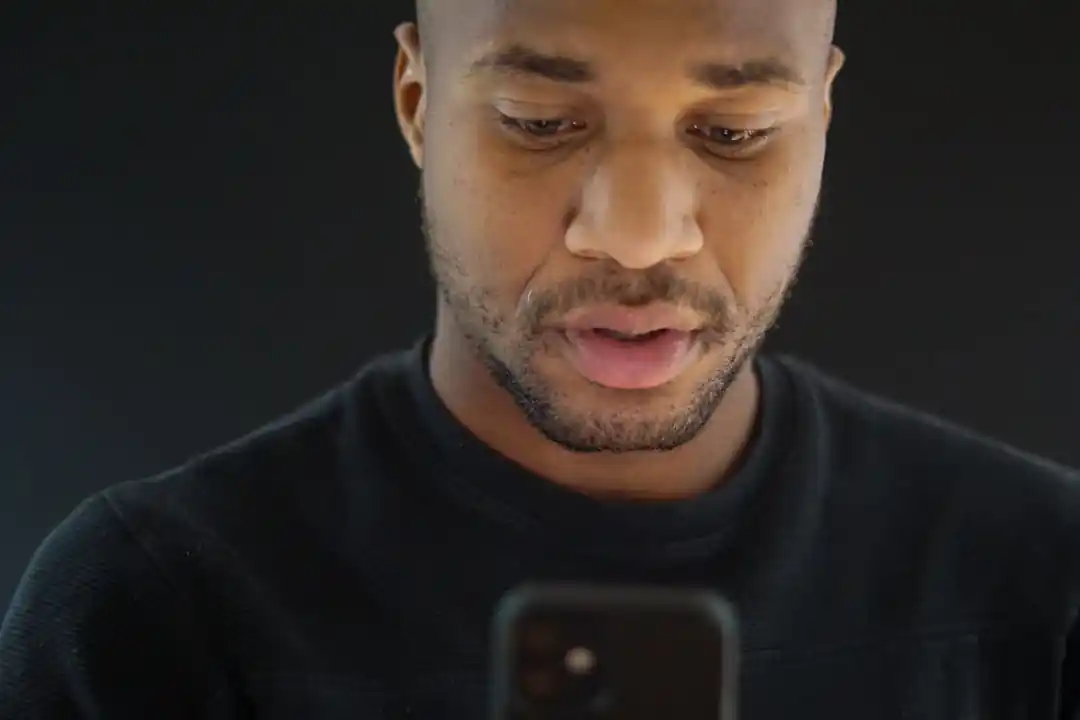 スマートフォンの画面を真剣な表情で見つめる人物のクローズアップ