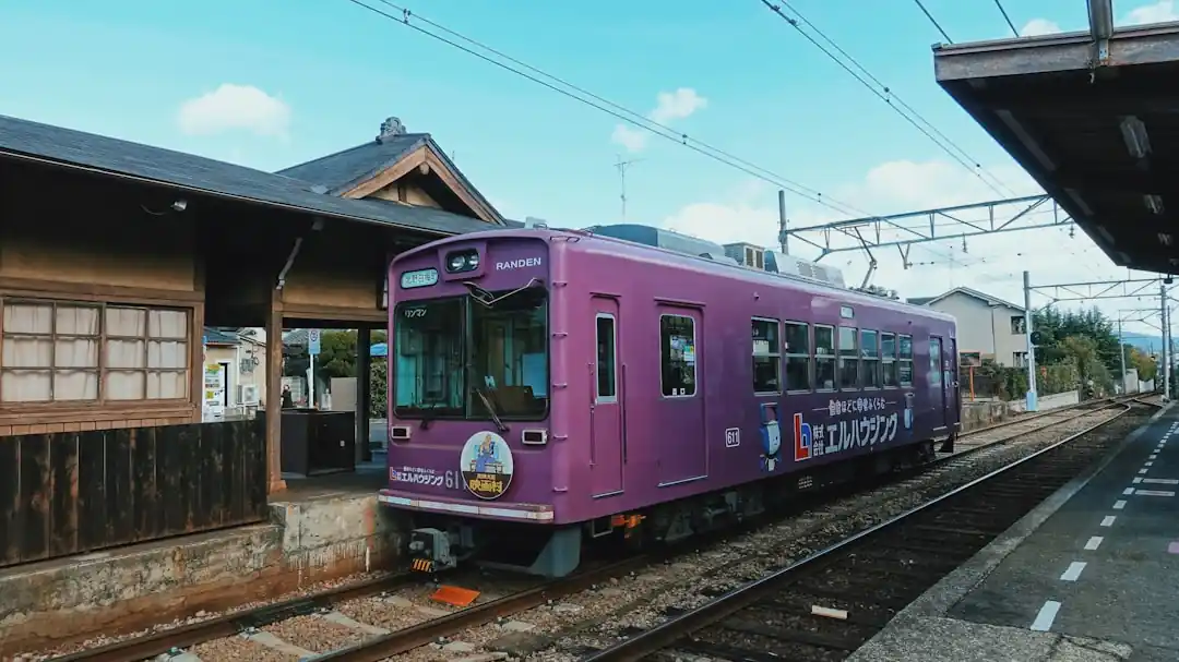 桜が咲き誇る駅に停車する、レトロで可愛らしいピンクと白の列車