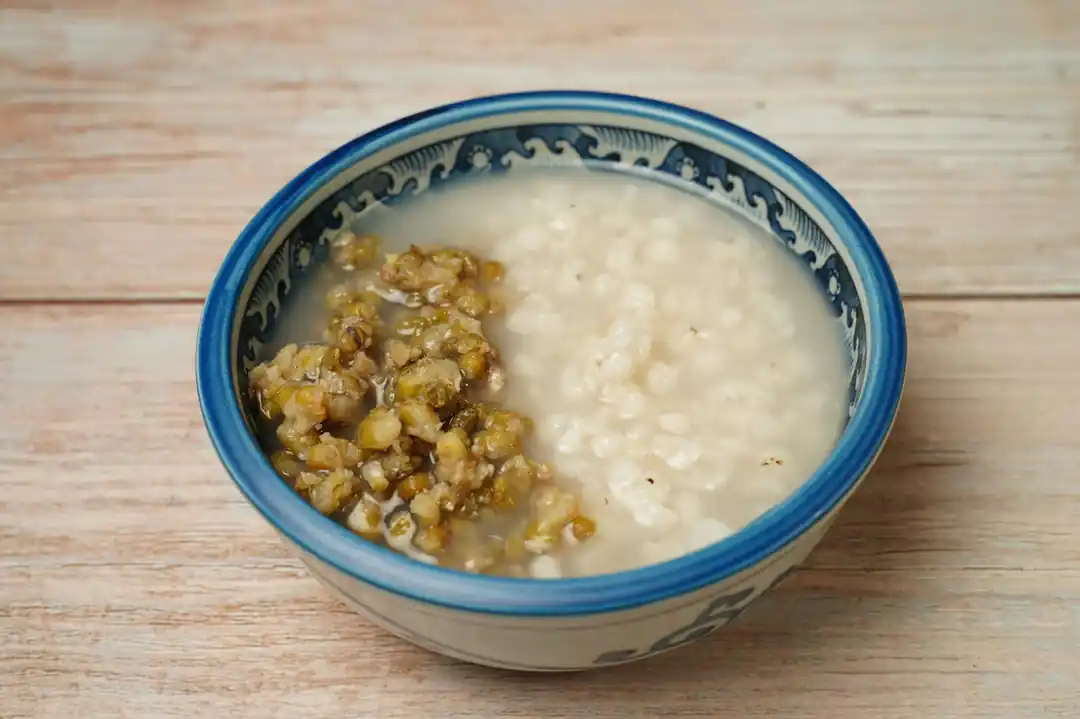 一個華麗的青花瓷碗中盛著綠豆粥,放在木質表面上。
