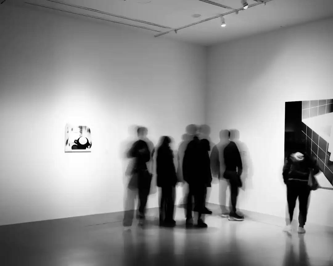 人們在一個藝術展覽中走動的黑白照片,呈現出動態的模糊效果。
