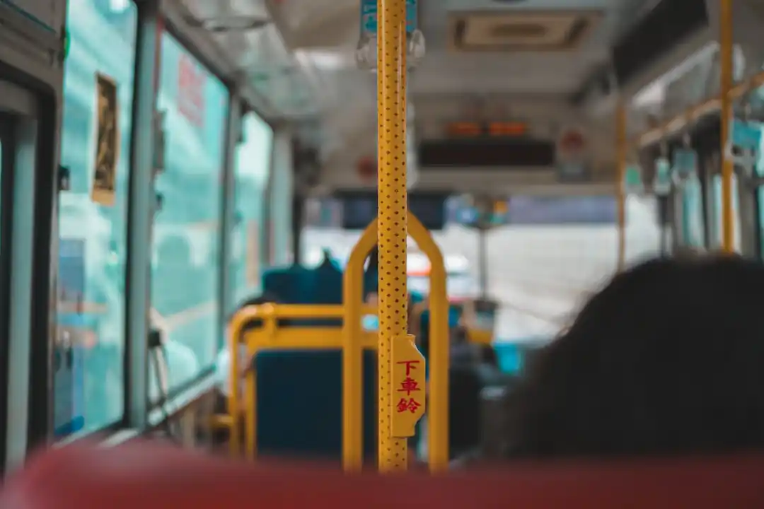 公車內部,乘客正準備刷卡,黃色的扶手和紅色的座椅形成鮮明對比。
