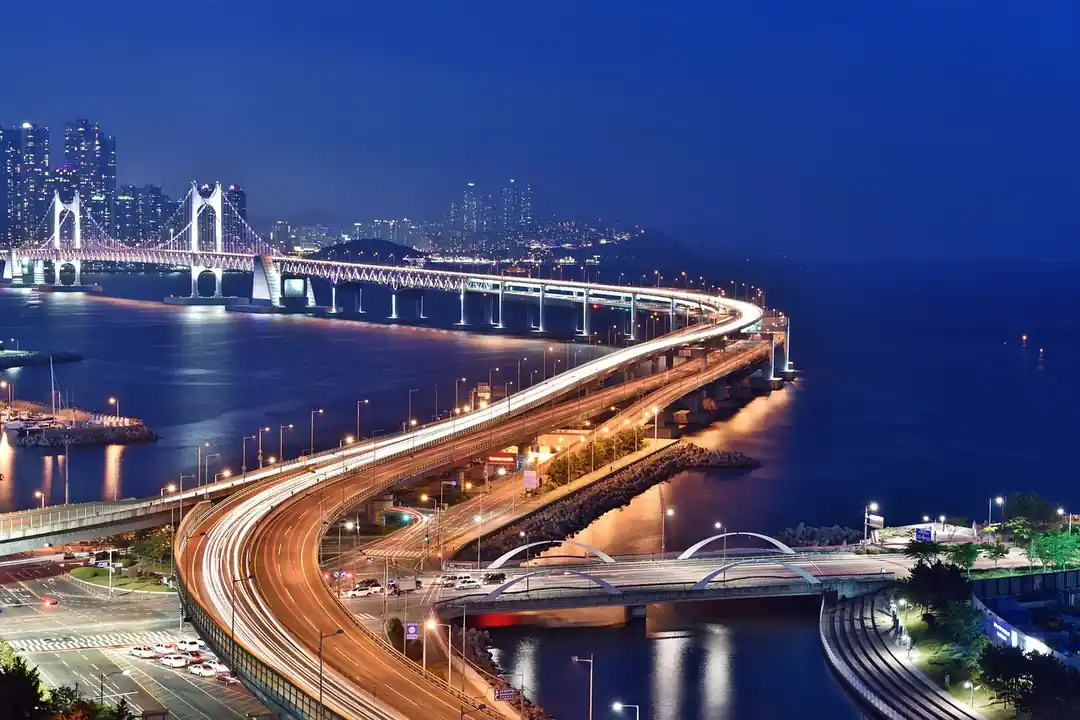 밤에 조명이 켜진 부산의 광안대교가 바다 위로 길게 뻗어있는 모습