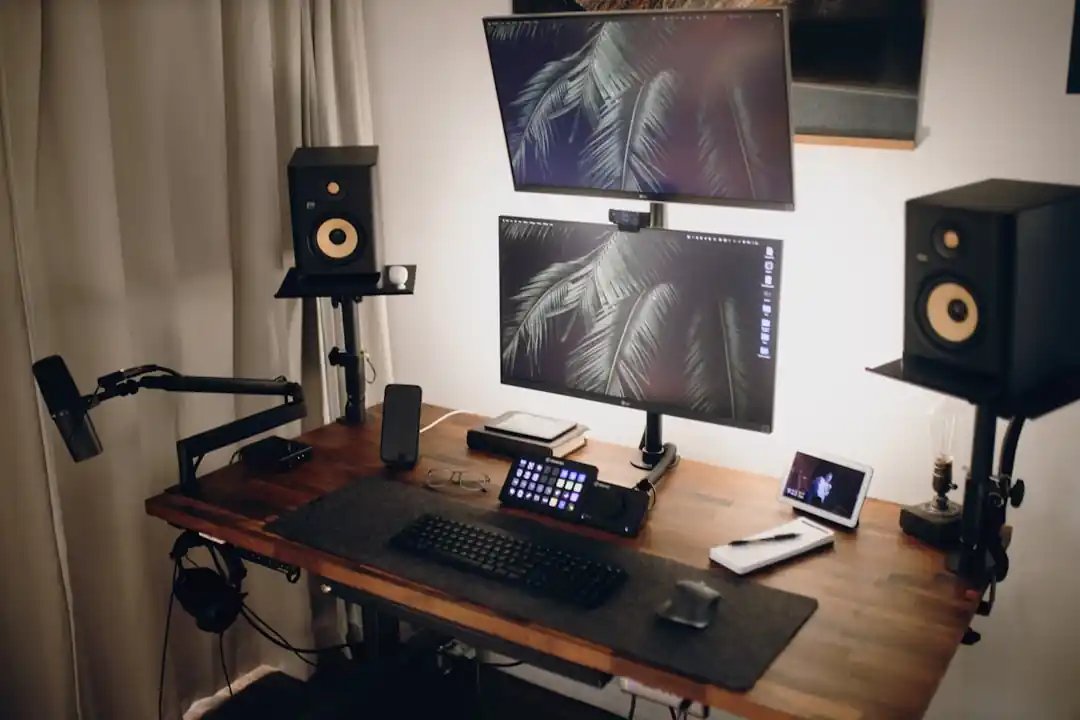 DAWソフトウェアが表示されたコンピューターモニター、スピーカー、MIDIキーボードが置かれた音楽制作用デスク