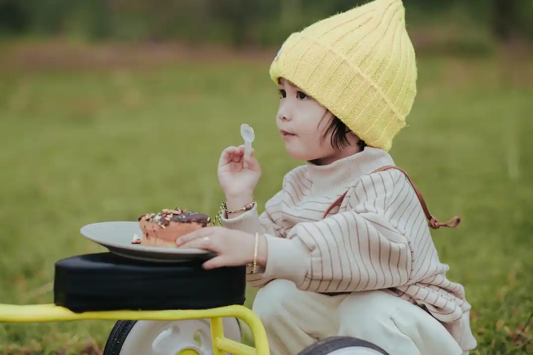 一個可愛的小孩在公園的野餐墊上吃東西。