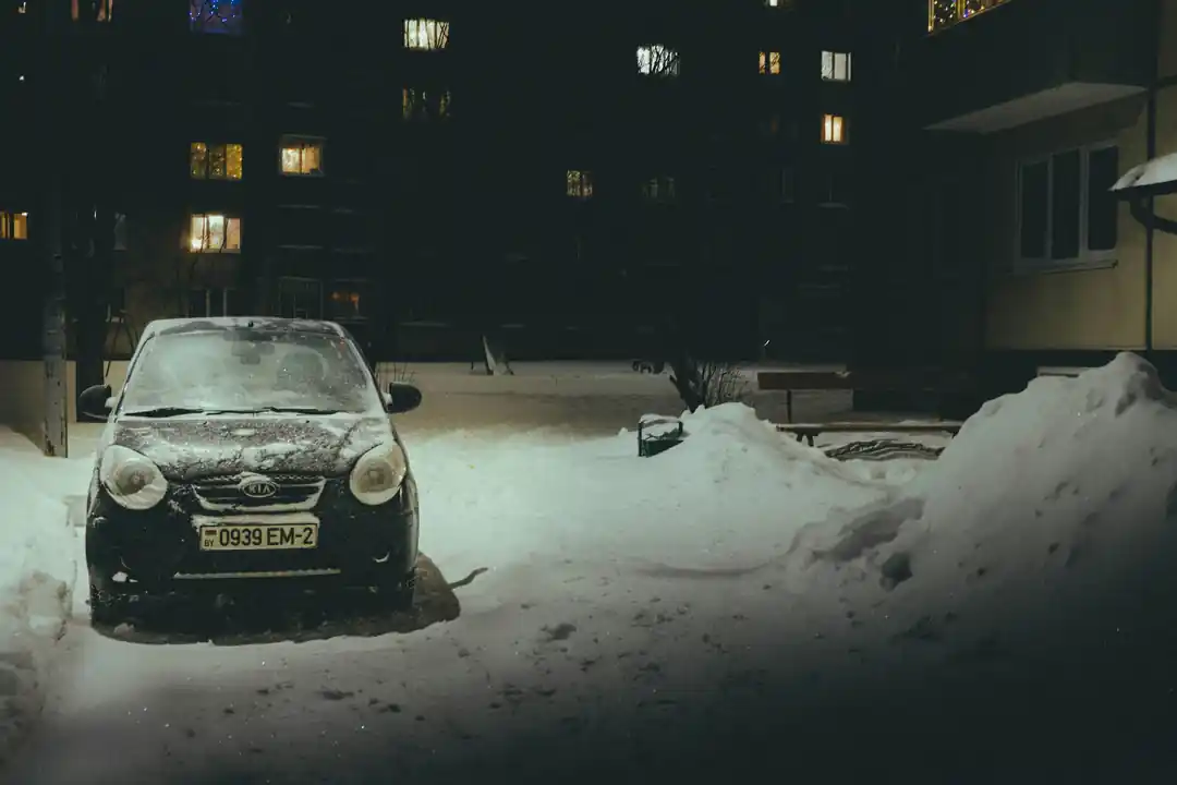 A car parked in the snow at night.