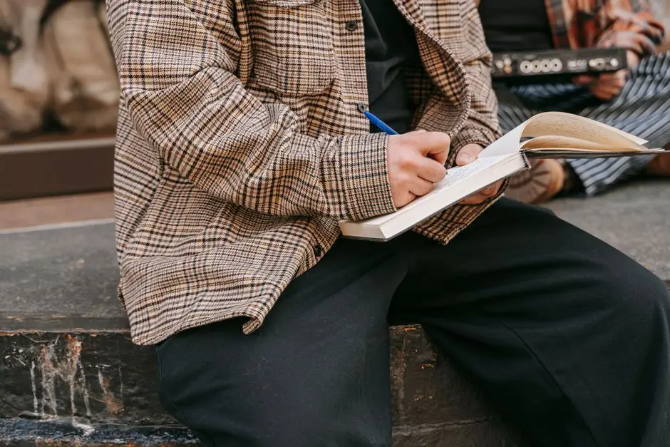 A person writing in a notebook outdoors on a sunny day