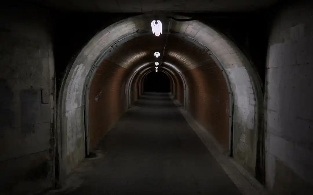 一條深夜裡的鐵路隧道,盡頭透出微光,給人一種深邃又未知的感覺。