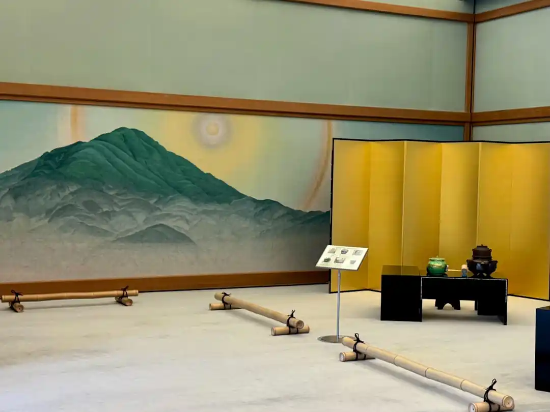 日本の伝統的な屏風と掛け軸が展示された美術館の展示室。落ち着いた照明が作品の繊細な美しさを引き立てている。
