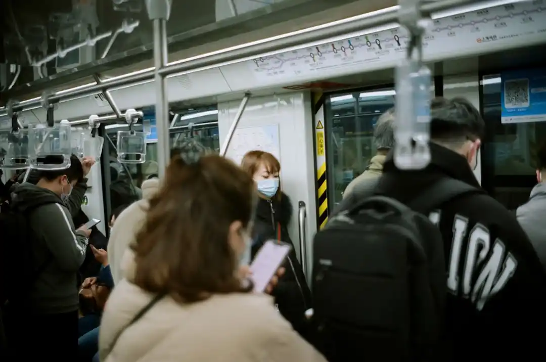 한 여성이 지하철 좌석에 앉아 창밖을 바라보고 있다.