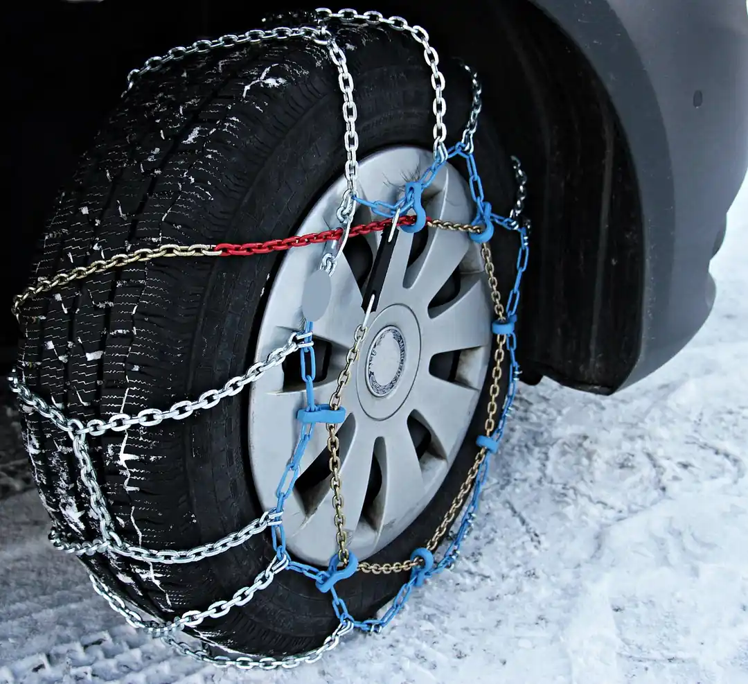 雪道でタイヤに装着された金属製のタイヤチェーンのクローズアップ