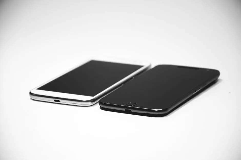 Two smartphones, one black and one white, on a white surface