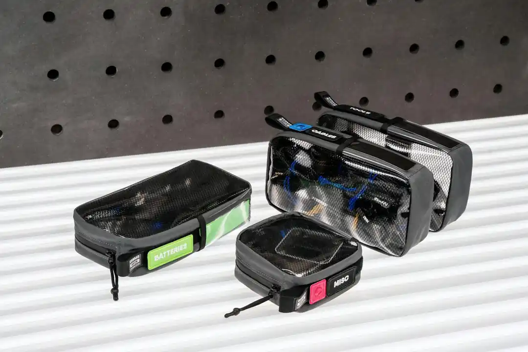 Mesh organizer bags with labels for cables, batteries, and miscellaneous items in a modern setting.