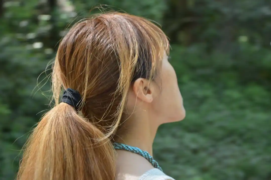 ブリーチされた髪とシャープな顎を持つ若い日本人女性がカメラから目をそらしている