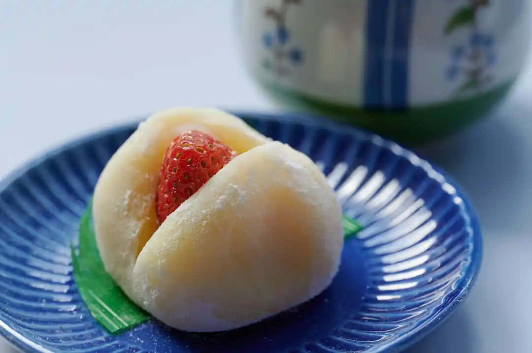 青い飾り皿に乗せられた、いちご大福のクローズアップ