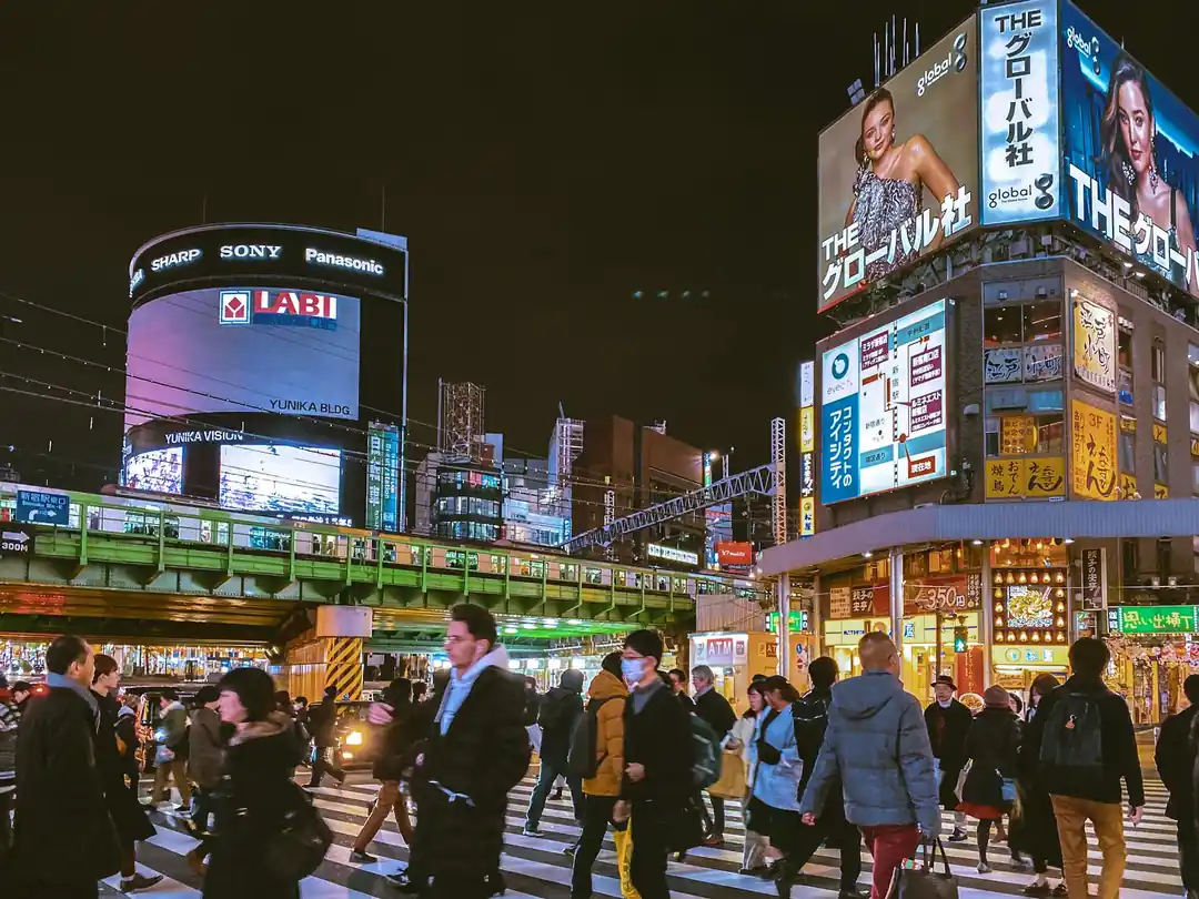 東京の渋谷交差点の賑やかな夜。活気ある人々とそびえ立つビルボードが特徴。