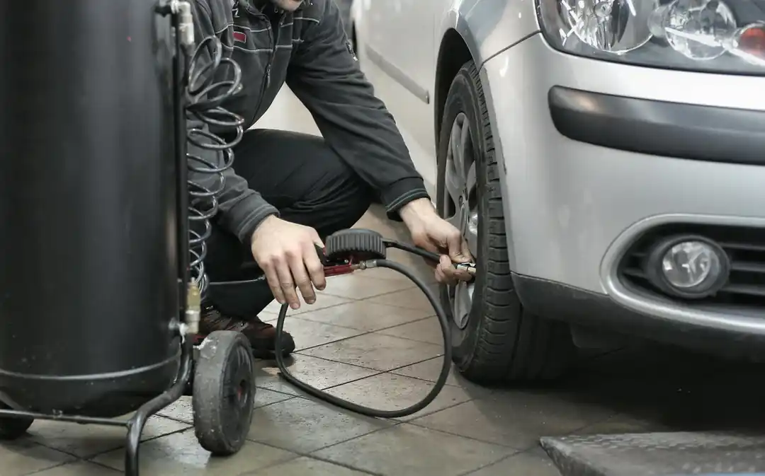 A mechanic uses an air hose to inflate a car tire in a garage.