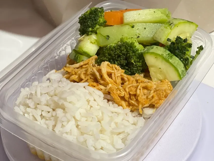 A meal prep container with shredded chicken, rice, and mixed vegetables.