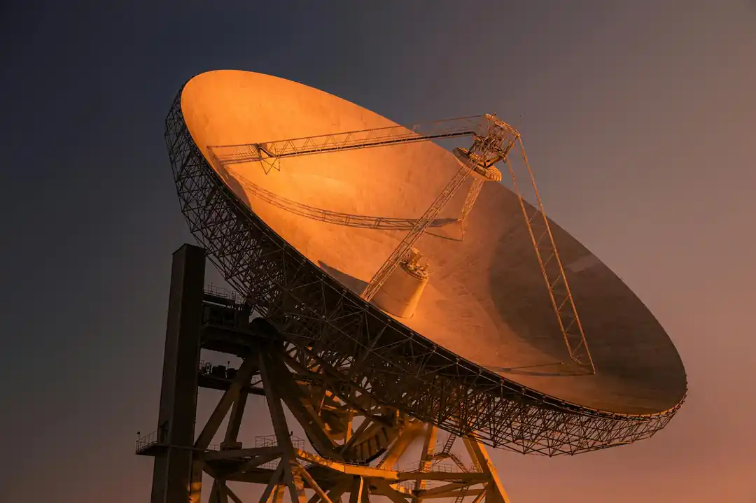 一座大型衛星地面接收站,在黃昏的金色陽光下指向天空。