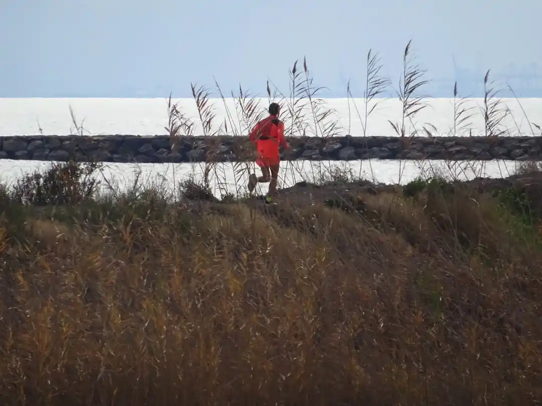 海辺をランニング中の男性が、ペースを確認するために腕時計を見ている様子。