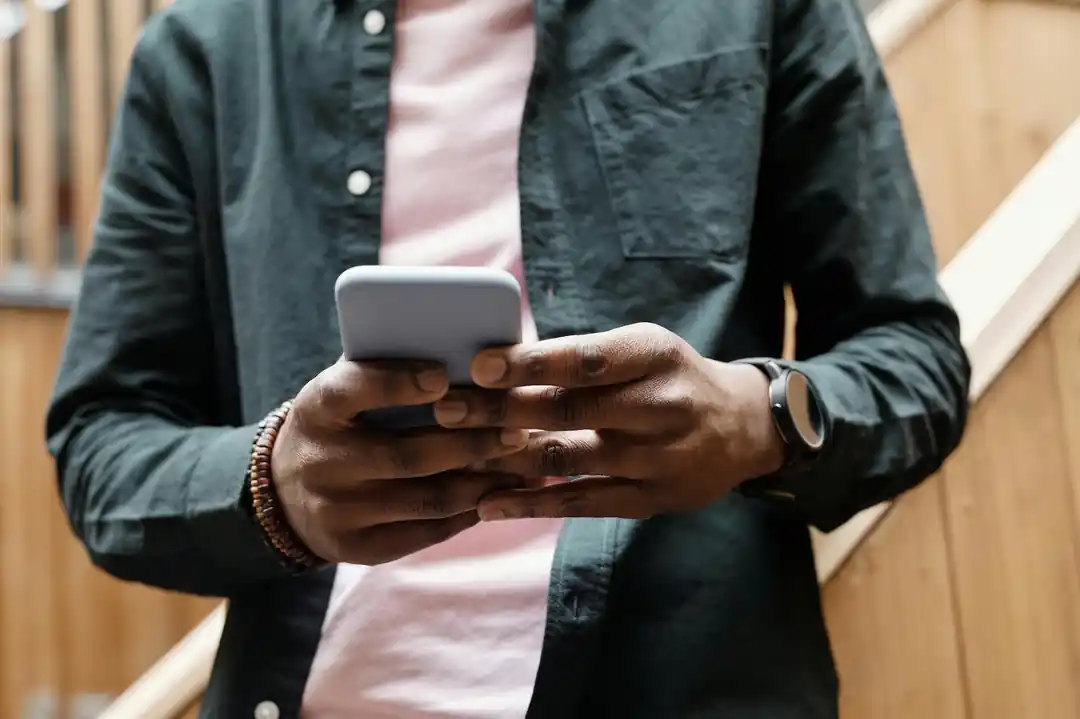 リラックスした雰囲気の室内で、スマートフォンの画面を操作する手のクローズアップ