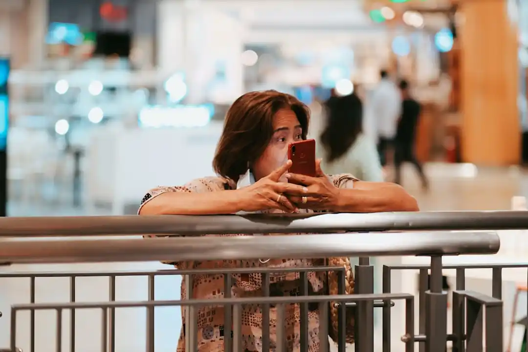 한 여성이 집 안에서 편안하게 스마트폰을 보며 온라인 쇼핑을 하고 있다.