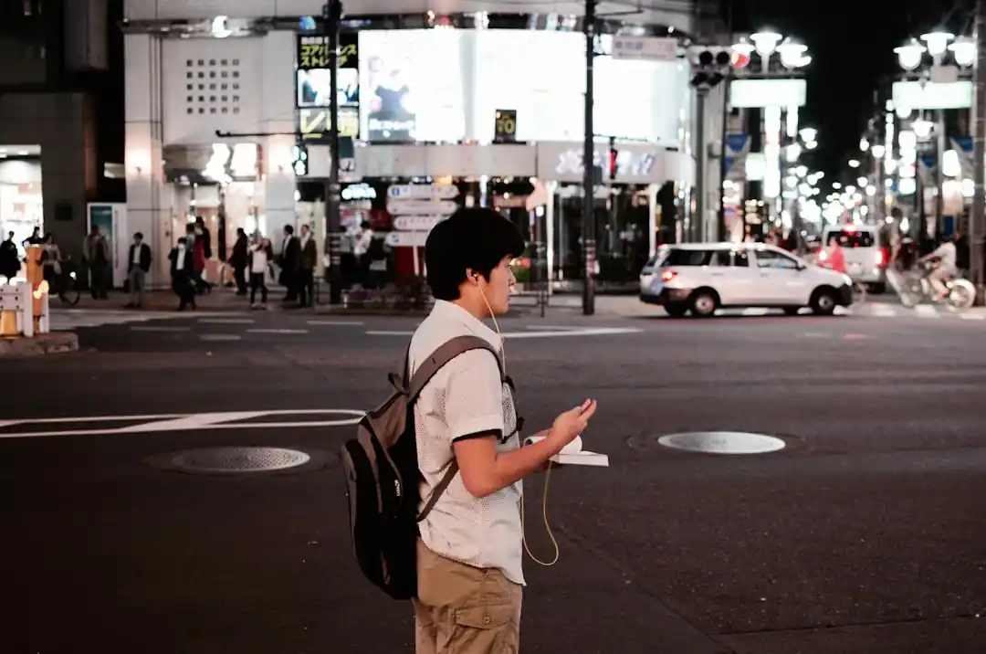 日本の街角でイヤホンをしながらスマートフォンを見つめる男性