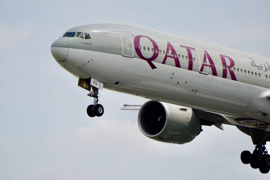 A close-up view of a Qatar Airways airplane's landing gear during flight against the sky.
