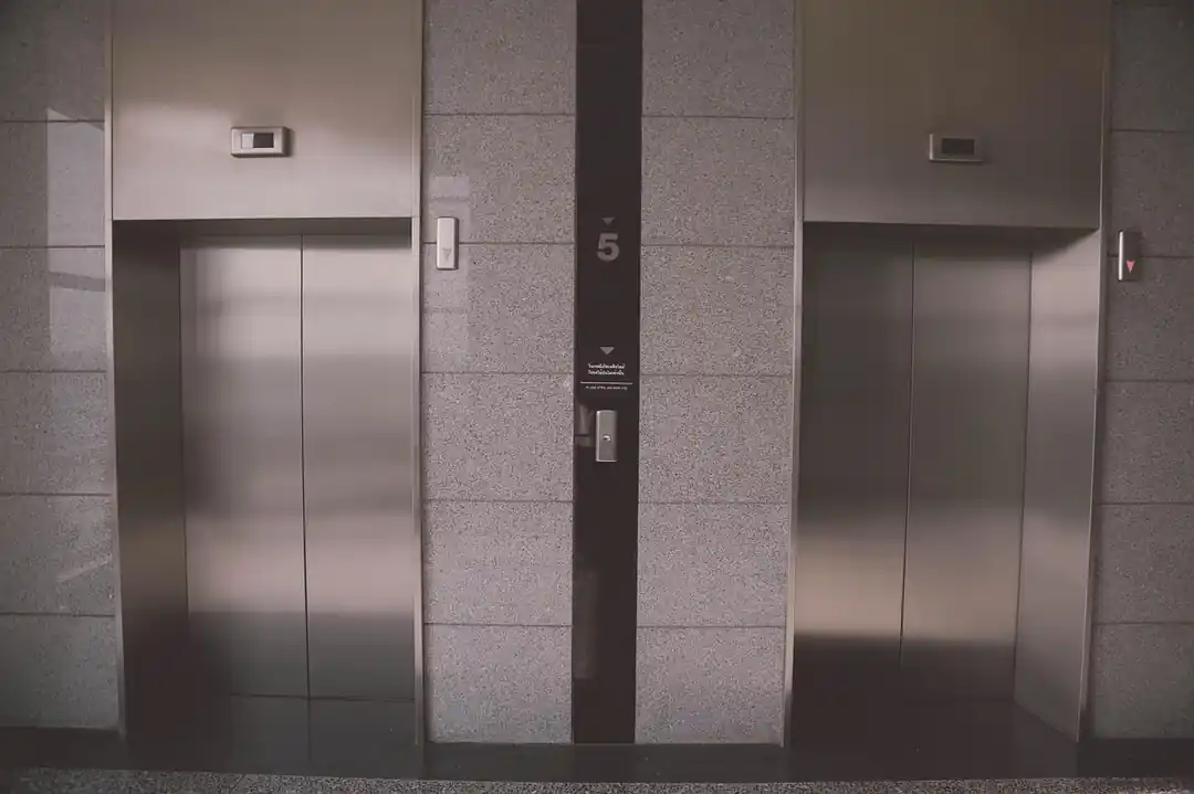 從電梯內部向外看,門外是模糊的城市高樓景觀。