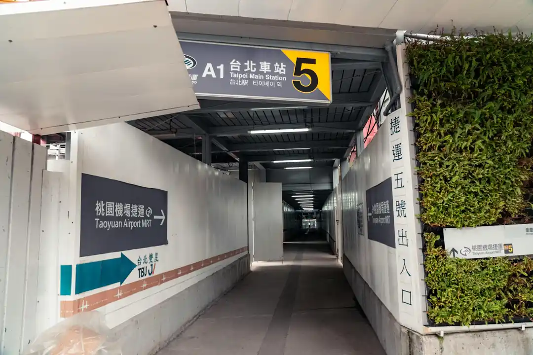 一個通往台北車站的遮蔽走道,指標清楚地指向桃園機場捷運的方向。
