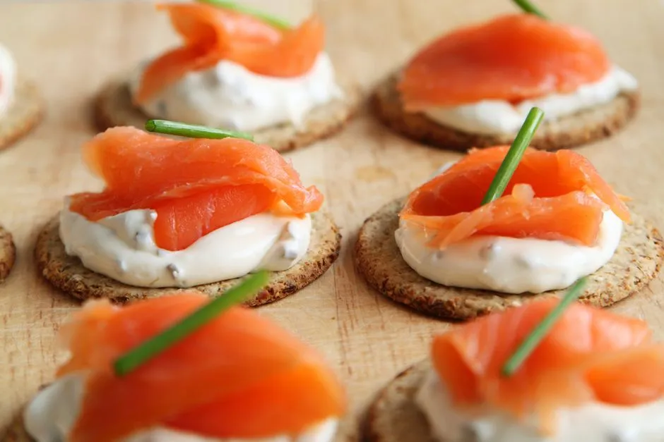 Small crackers topped with cream cheese and slices of smoked salmon.