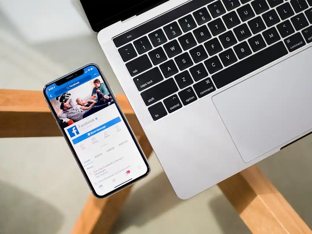 一支iPhone X放在MacBook旁邊,螢幕上顯示著社群媒體的動態牆。