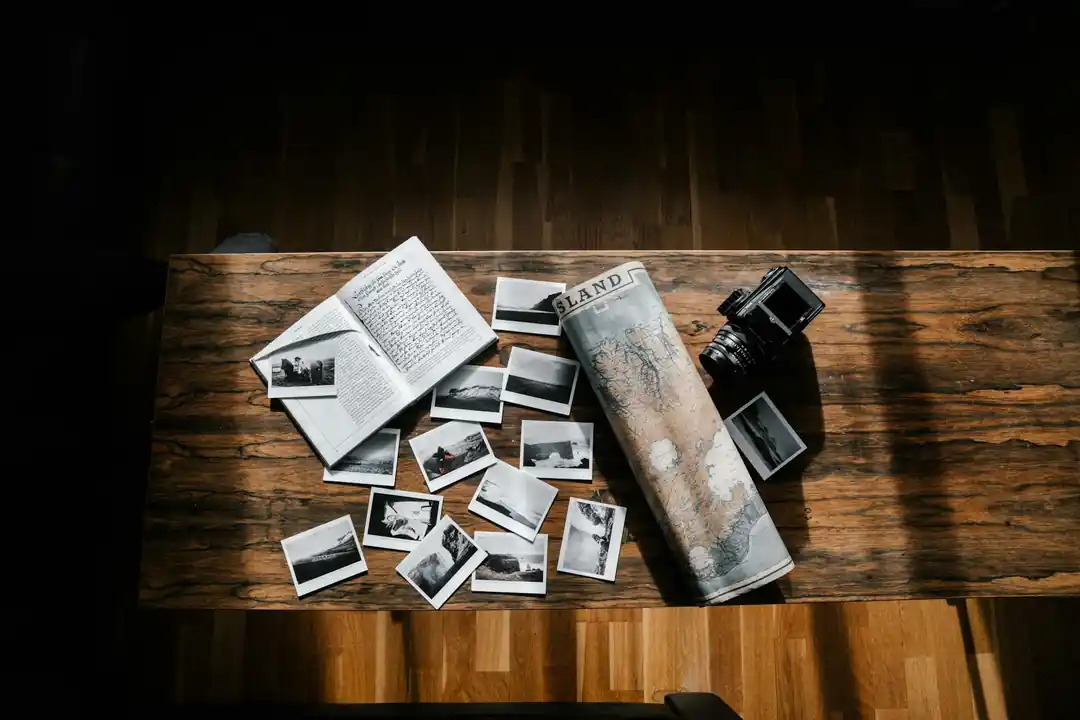 木製のテーブルの上に広げられた日記、写真、カメラ、地図