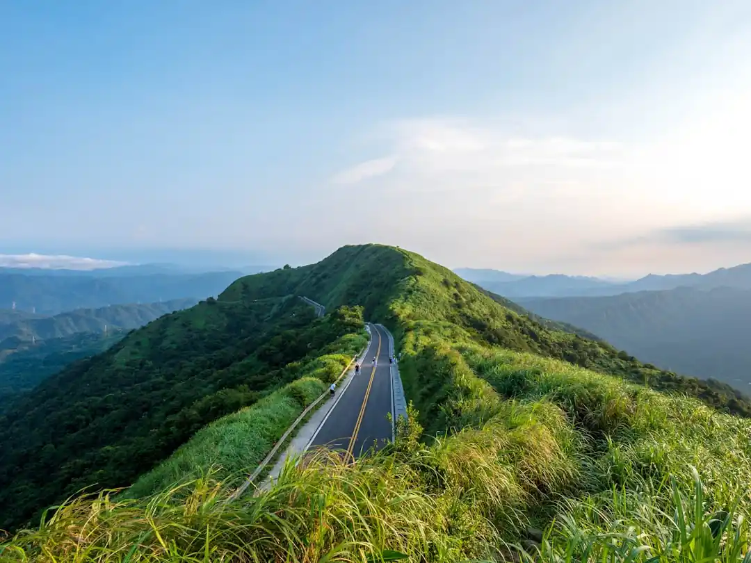一條空曠的公路延伸至遠方的綠色山脈下。